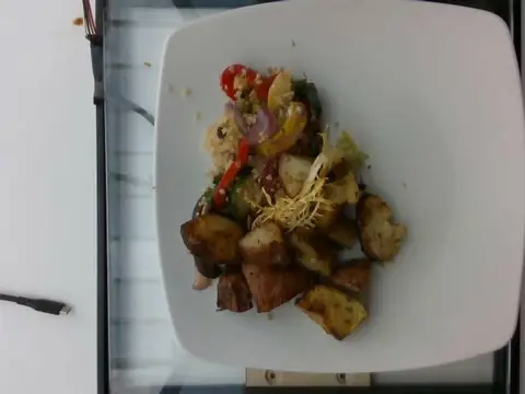 Roasted potatoes with quinoa and vegetables on a white plate.